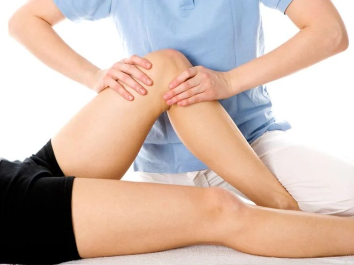 Clinician examining a patient’s knee on an exam table